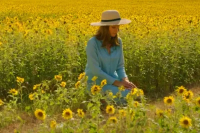 Figura arrodillada entre girasoles bajo el sol