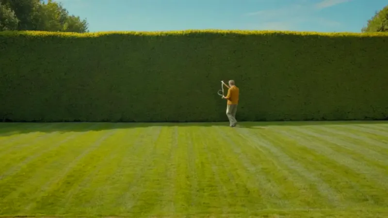 Una figura poda un seto al sol